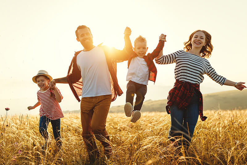 happy family joyfully running together in a sunlit field.